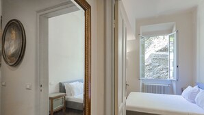 Un dormitorio con cama, una mesita de noche, un espejo y una ventana con vistas a un paisaje rocoso.