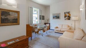 Una sala de estar con una mesa de comedor de vidrio, sofá blanco y obras de arte en las paredes.