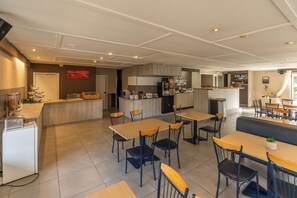 A modern kitchen with a central island, dining tables, and chairs. - Sleep & Go Brugge (Bruges)