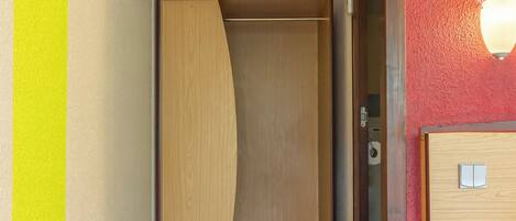 Habitación de hotel con un armario de madera, una cama y un equipo de aire acondicionado instalado en la pared.