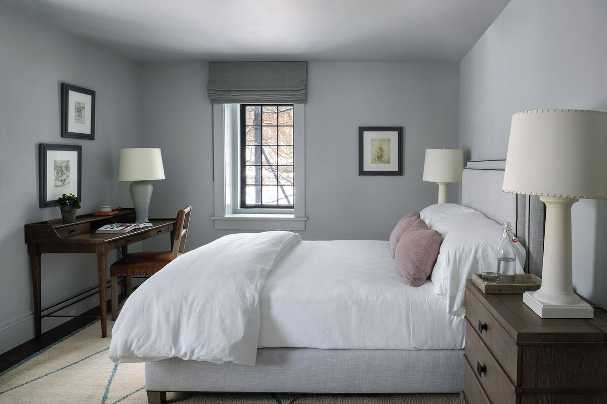 Un dormitorio con cama, mesitas de noche, un escritorio y una ventana.