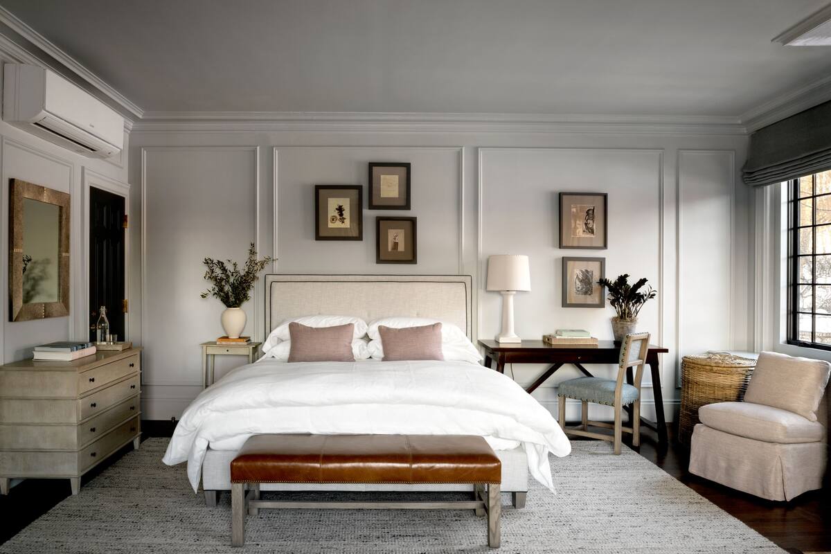 Un dormitorio con una cama grande, una mesita de noche, una silla y una ventana.