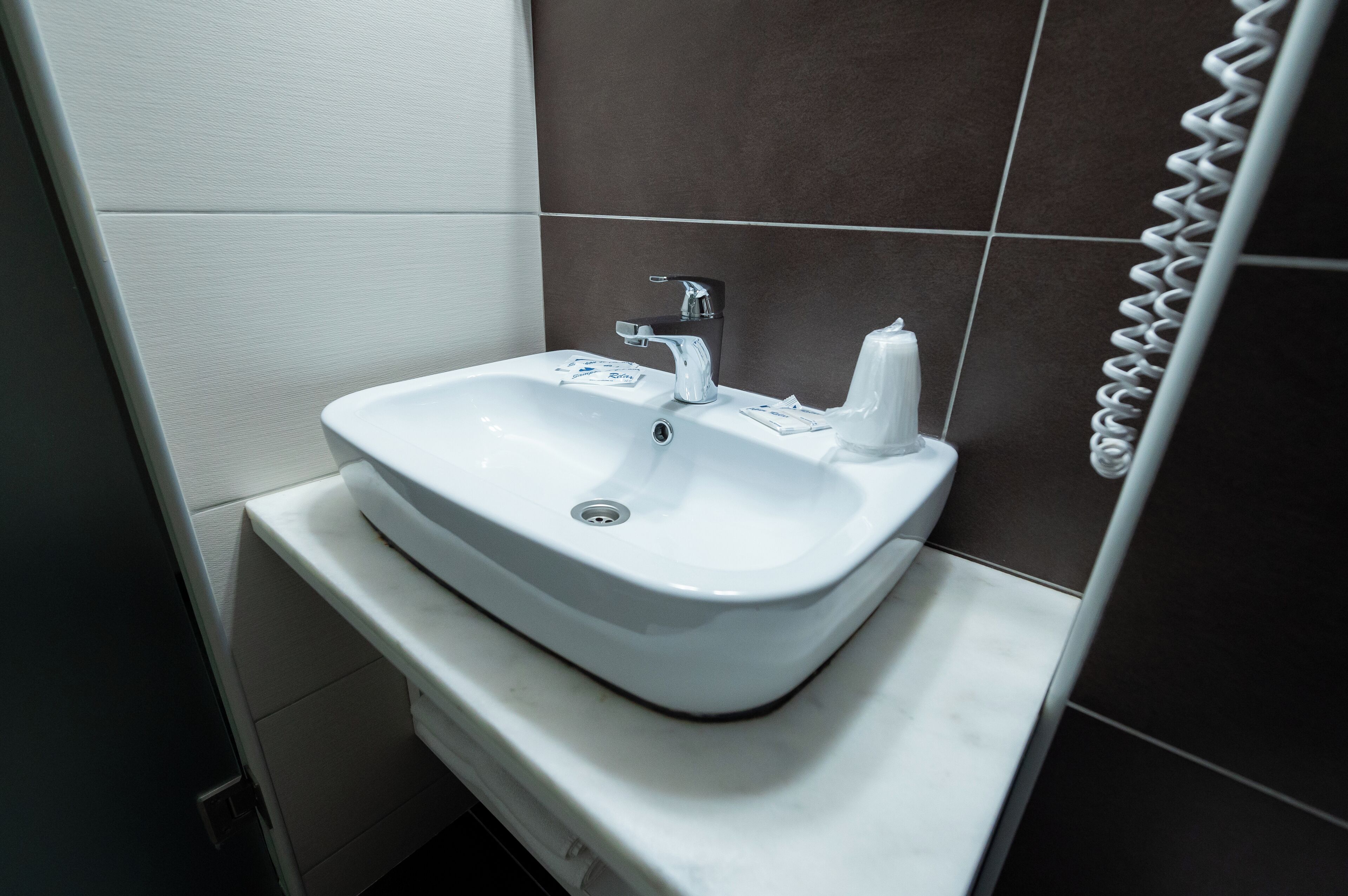 A white bathroom sink with a chrome faucet, a soap dispenser, and a tissue box on a white countertop.
