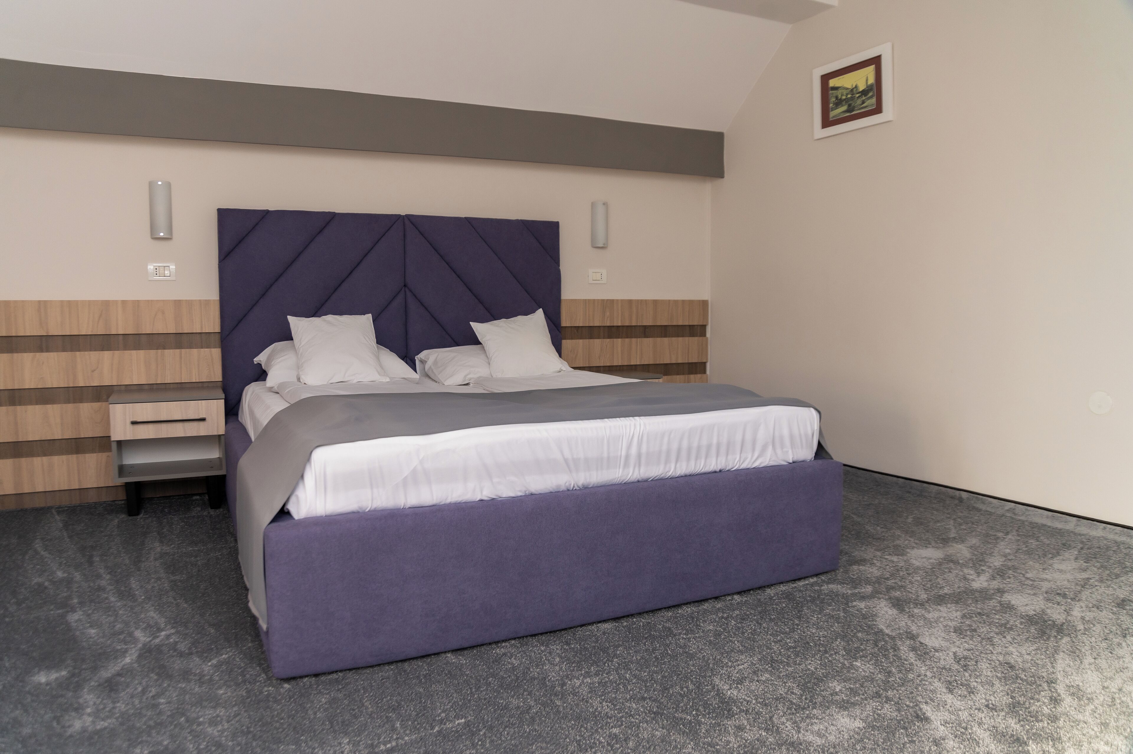 Un dormitorio moderno con una cama grande, una mesita de noche y una lámpara de pared.