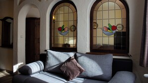 Una sala de estar acogedora con un sofá, una ventana decorada con un frutero y un armario de madera.
