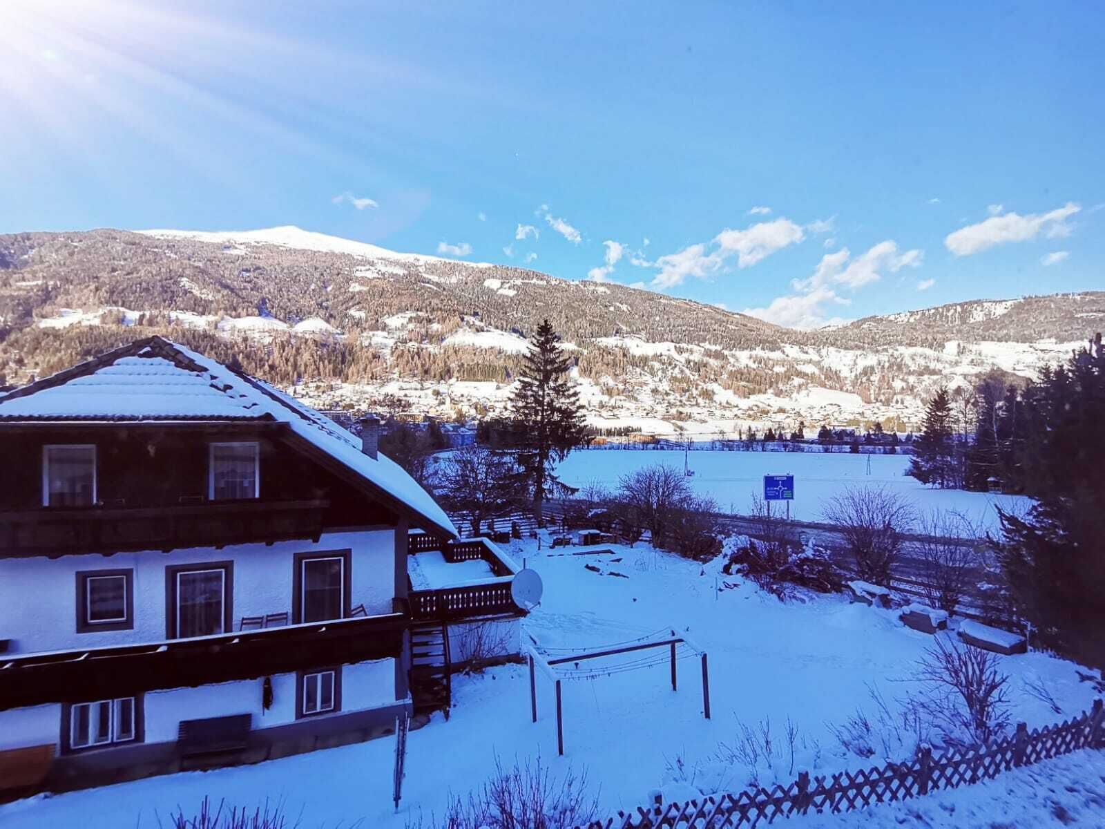 A chalet with a balcony overlooking a snowy landscape and a lake.