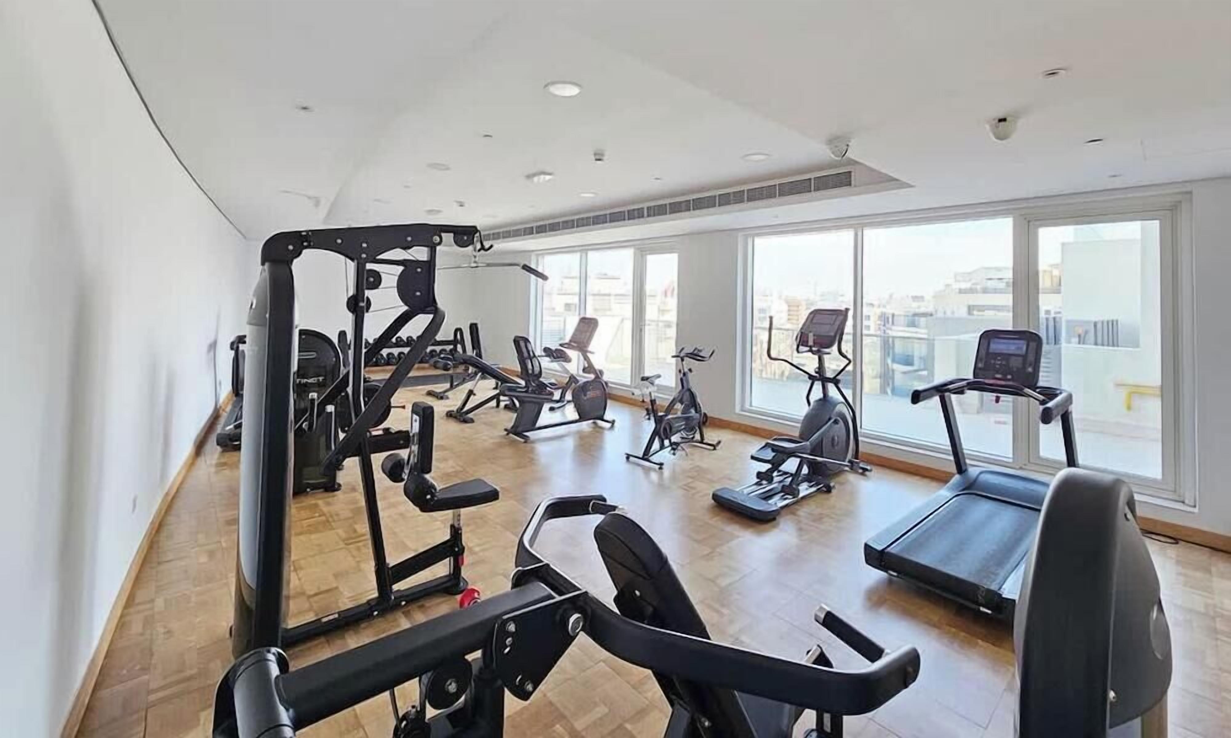 A gym with various exercise equipment, large windows, and a view of the city.