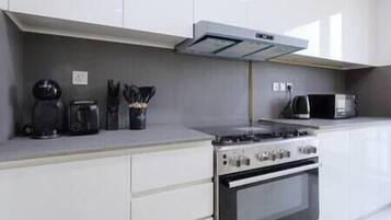 A modern kitchen with white cabinets, a gas stove, a microwave, and a coffee maker.