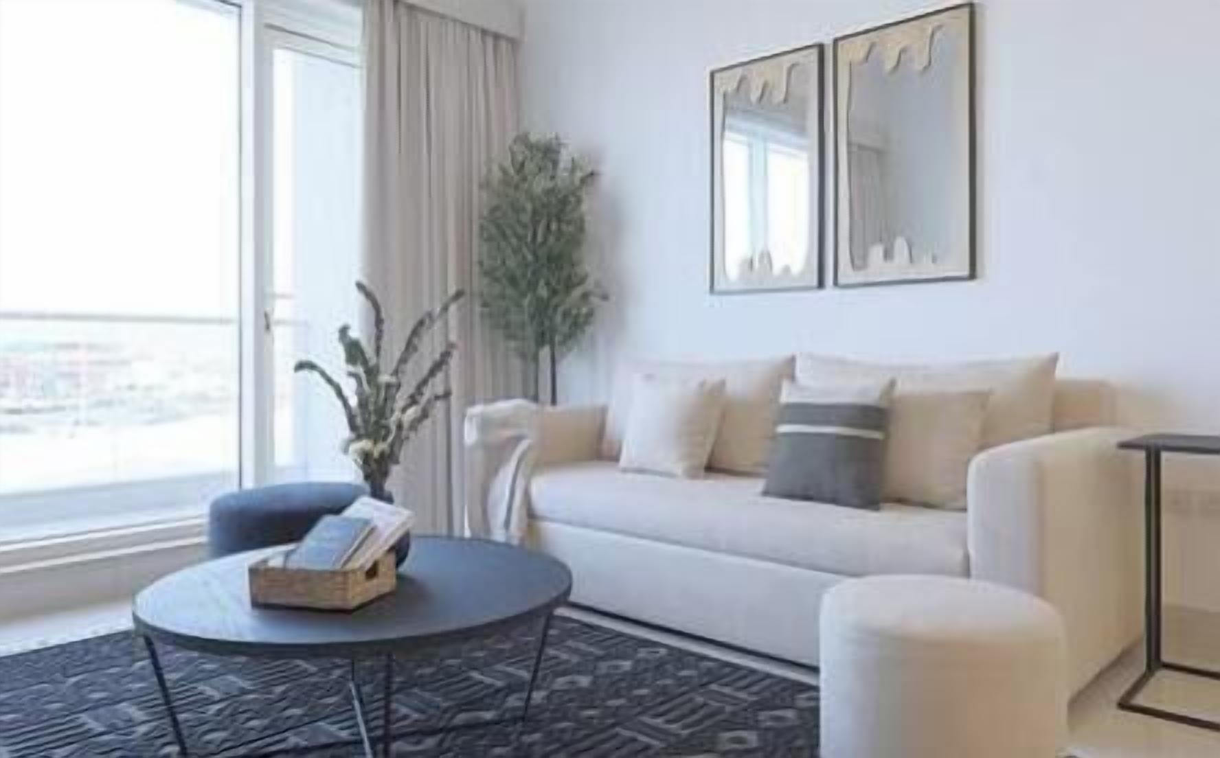 A modern living room with a sofa, a round coffee table, and a potted plant.