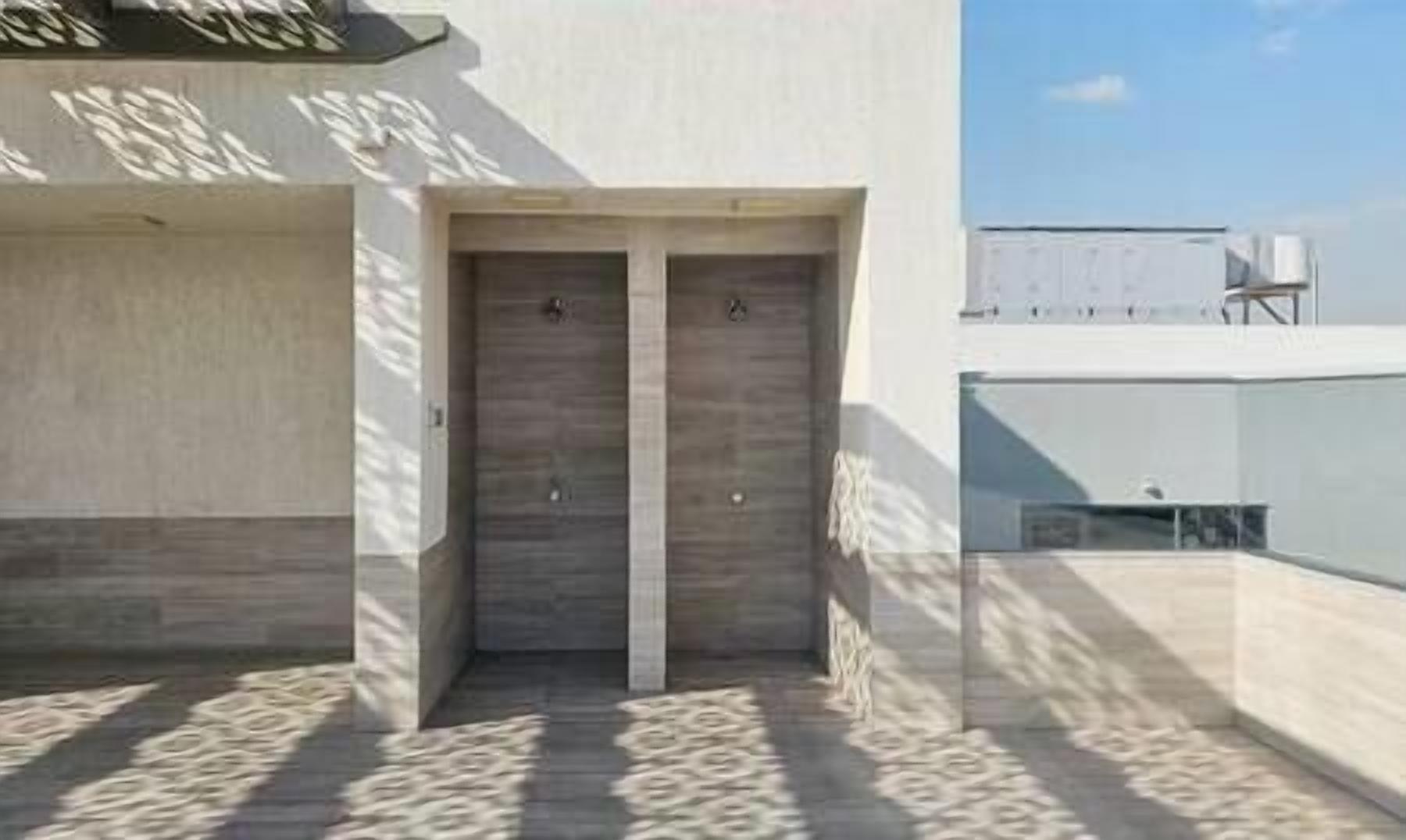 A building entrance with a double door, a concrete wall, and a shadow pattern on the ground.