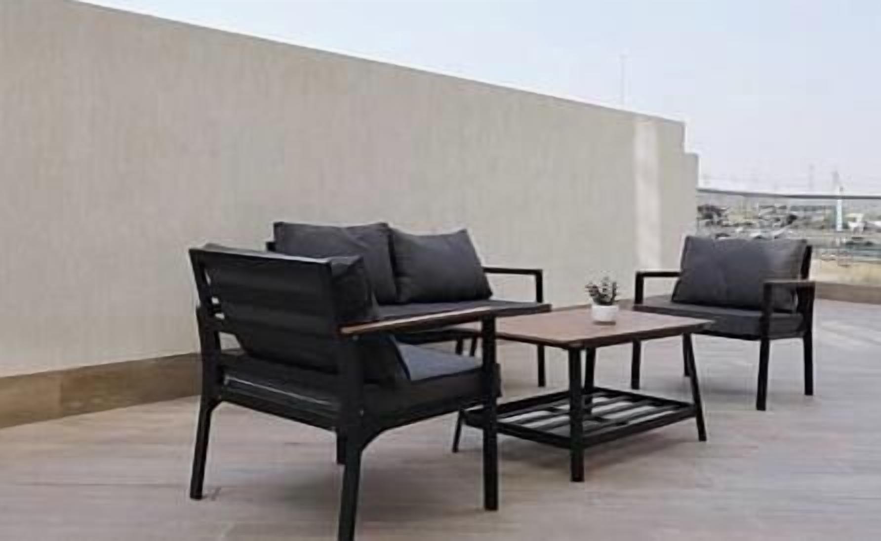 A rooftop terrace with two black chairs and a small table.