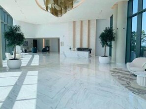A spacious lobby with a marble floor, seating areas, and large windows allowing natural light.
