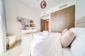 A modern bedroom with a large bed, a built-in wardrobe, and a bedside table. - Bluewaters Oceanview Apt w/ Infinity Pool & Gym (Dubai)