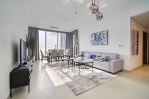 A modern living room with a sofa, coffee table, and TV. - Bluewaters Oceanview Apt w/ Infinity Pool & Gym (Dubai)