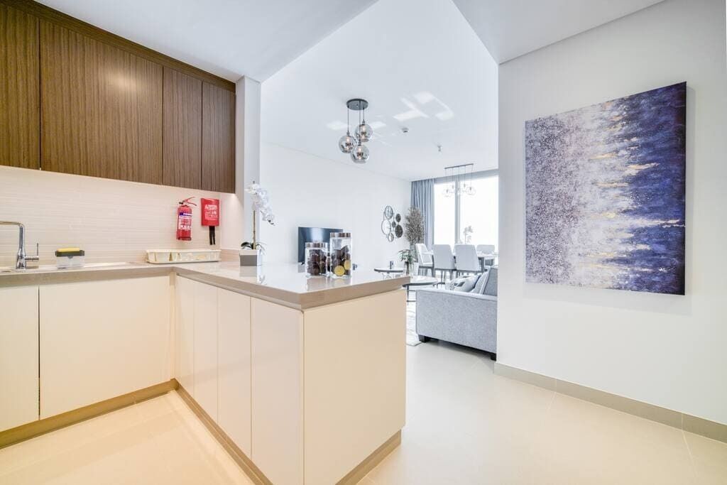 Una cocina moderna con una isla central, armarios de madera y un comedor con sofá y sillas.