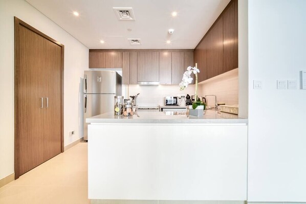 A modern kitchen with a central island, built-in appliances, and wooden cabinetry.