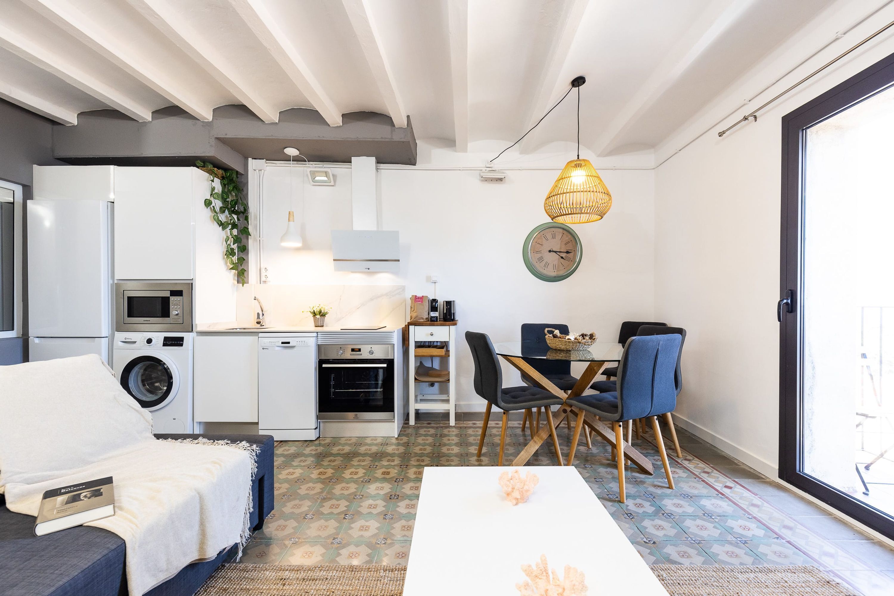 Un espacio habitable compacto con kitchenette, comedor y sofá.