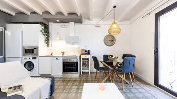 Un espacio habitable compacto con kitchenette, comedor y sofá.