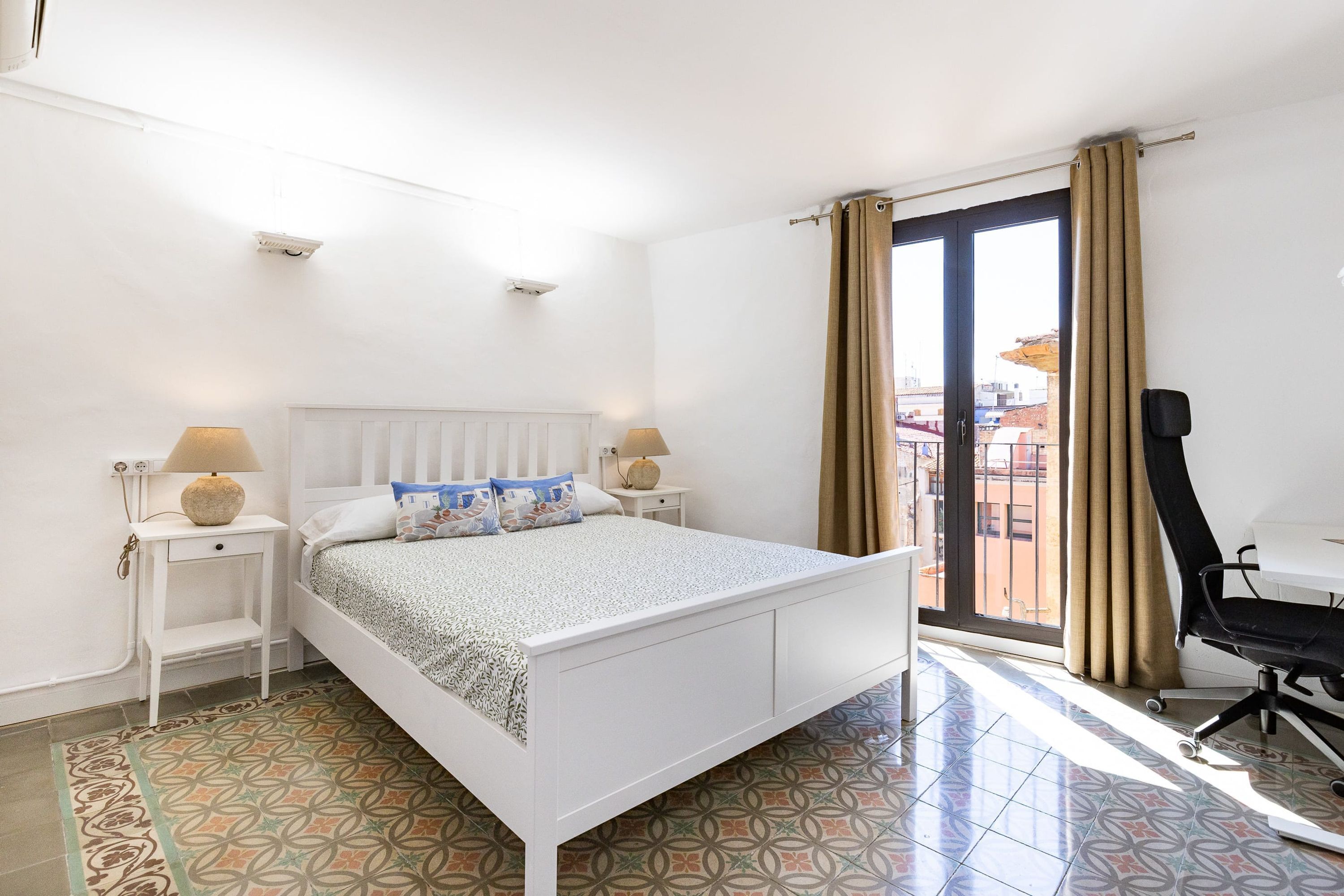 A bedroom with a bed, two bedside tables, a desk, and a chair.