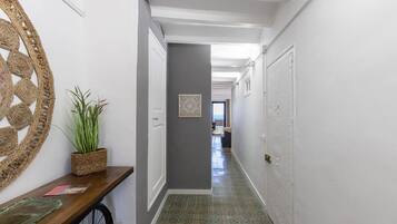 A hallway with a wooden bench, a potted plant, and a decorative wall piece.