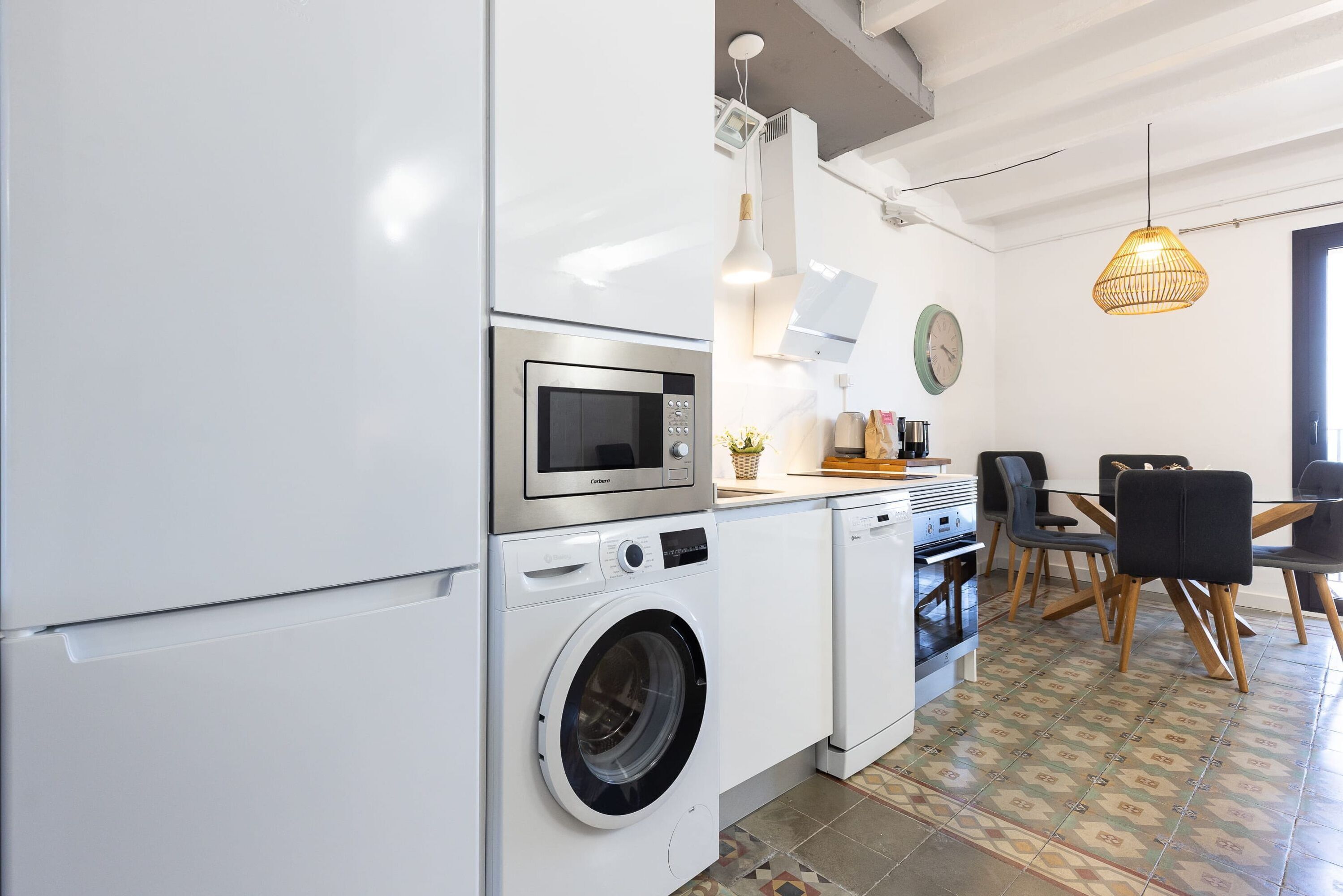 Une cuisine compacte équipée d’un lave-linge, d’un four à micro-ondes et d’un four traditionnel. Elle comprend également un coin repas avec une table et des chaises.