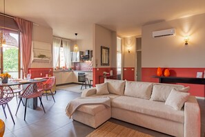 Un salon moderne comprenant un canapé, un coin repas, une cuisine et un mur d’accent de couleur rouge.