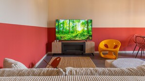 A living room with a flat-screen TV on a stand, a red and white wall, a yellow chair, and a sofa with a textured throw. - Urban House - 301 in Monza (Monza)
