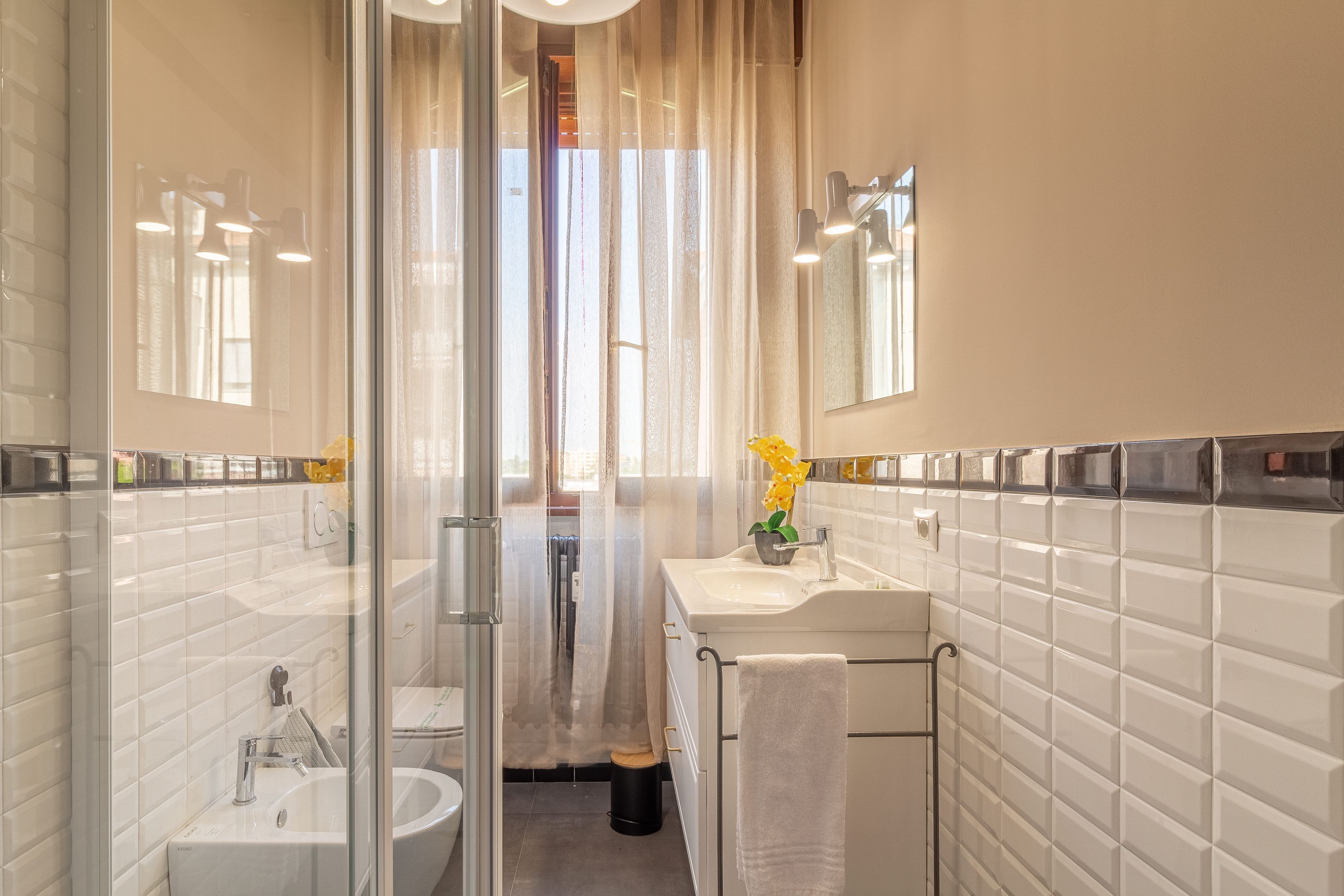 A modern bathroom with a glass shower enclosure, a sink, and a mirror.