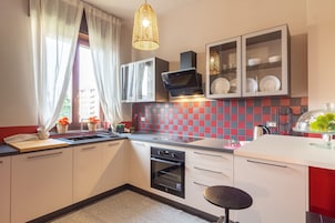 Una cocina moderna con horno empotrado, un lavamanos y una zona de comedor con una silla.
