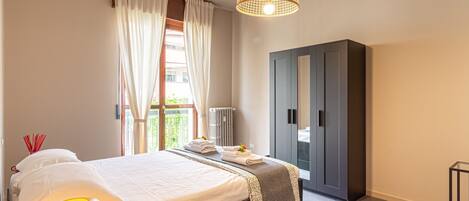 A bedroom with a bed, a wardrobe, a radiator, and a hanging light fixture.
