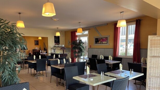 Een restaurant met meerdere tafels en stoelen, een keukenhoek en een groot raam met gordijnen.