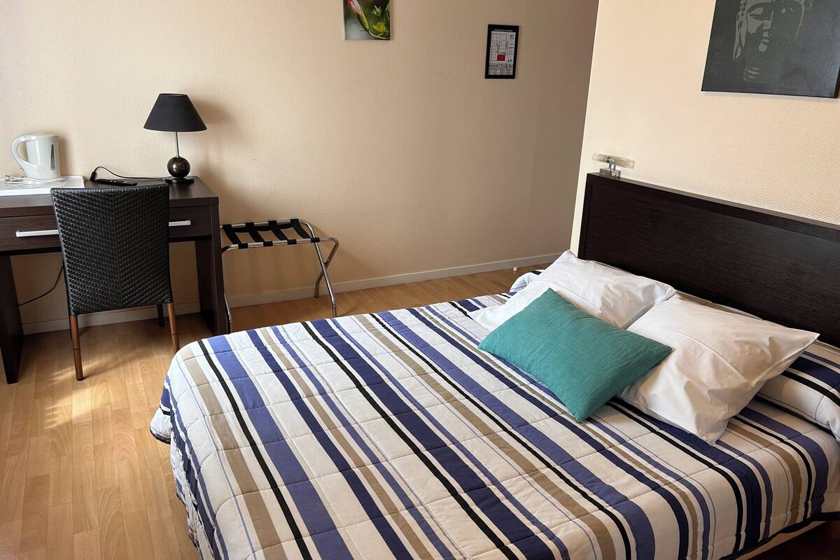Una habitación de hotel con cama, escritorio, silla y lámpara.