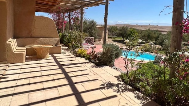 A covered patio area with a pool, outdoor seating, and a view of the landscape. - Les dunes de Guemassa (Gmassa)