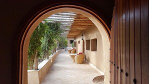 A corridor with a wooden ceiling, a view of the outdoors, and a door on the right. - Les dunes de Guemassa (Gmassa)