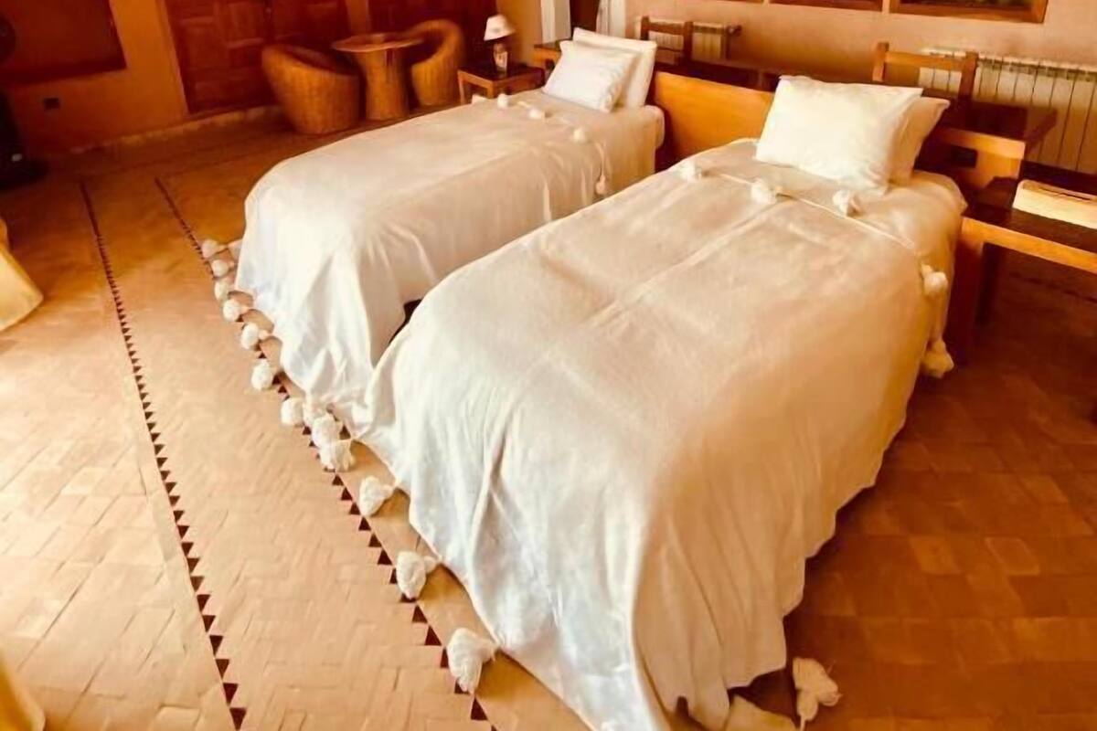 Une chambre avec deux lits, un plancher en bois et un décor traditionnel.