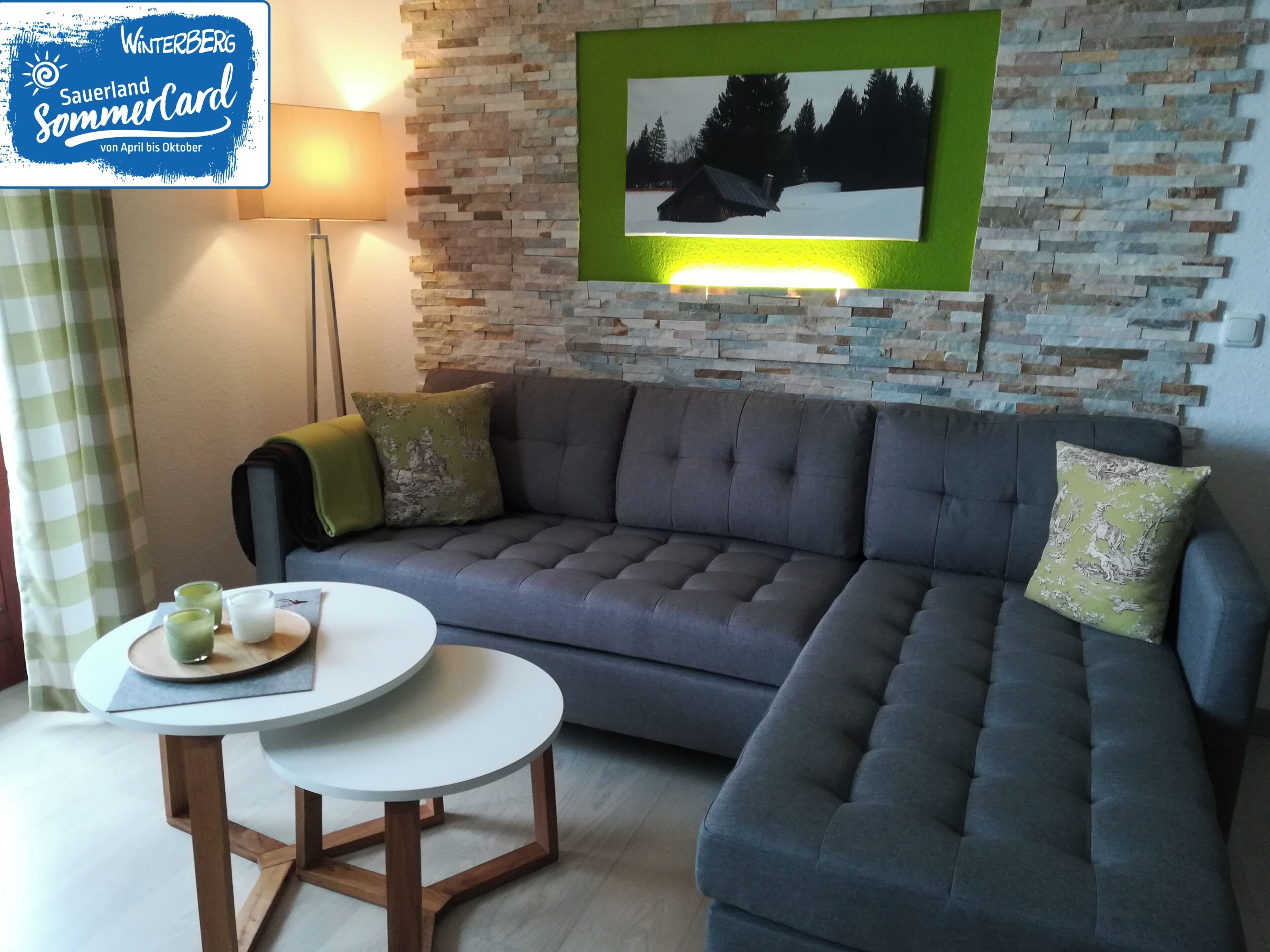 A modern living room with a grey sofa, a round coffee table, and a framed picture on the wall.