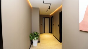 A modern hallway with a wooden floor, a potted plant, and a ceiling light fixture. - Perla Del Sol (Vlorë)