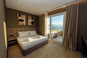 A modern hotel room with a large bed, a view of the sea, and a balcony with curtains. - Perla Del Sol (Vlorë)