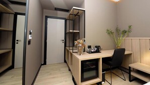 A modern, compact room with a wooden desk, black chair, and a small plant. - Perla Del Sol (Vlorë)