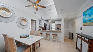 A kitchen with a dining area, featuring a ceiling fan, a dining table with chairs, and a kitchen island with stools. - Beach Castle Resort, 2nd Floor, Updated, Walk to Beach/Bay, Pool (Longboat Key)