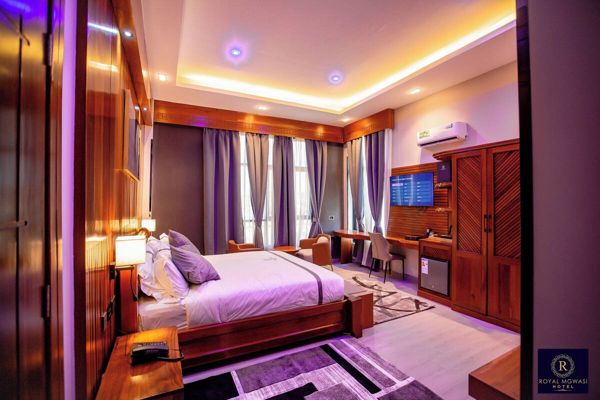 Quarto de hotel moderno com uma cama grande, uma escrivaninha e uma televisão.