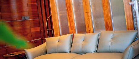 A beige leather sofa with a wooden wall and a woven wall hanging in the background.