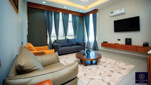 Een moderne woonkamer met een bank, een salontafel en een flatscreen tv aan de muur.