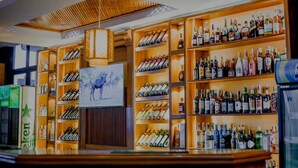 Een bar met drankflessen op de planken, een schilderij van zebra's en een plafondlamp.