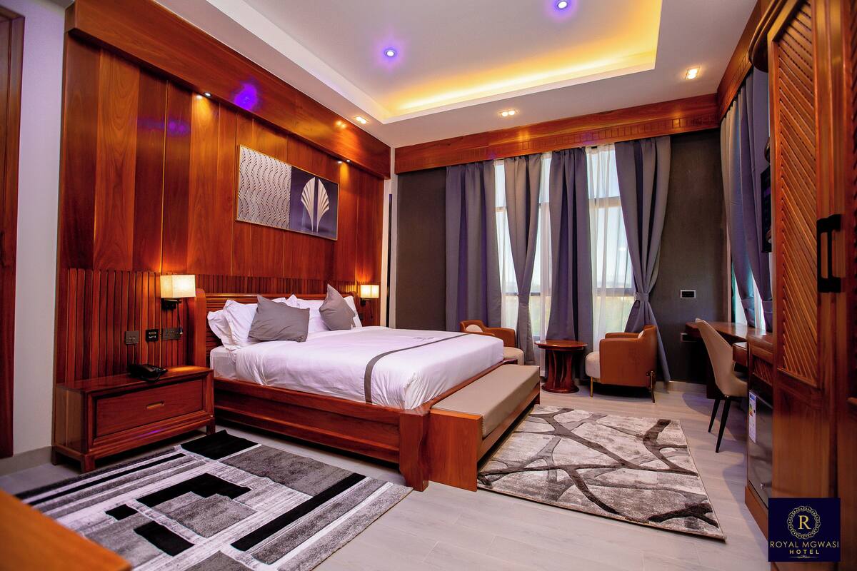 Quarto de hotel com cama de madeira, uma escrivaninha e uma cadeira.