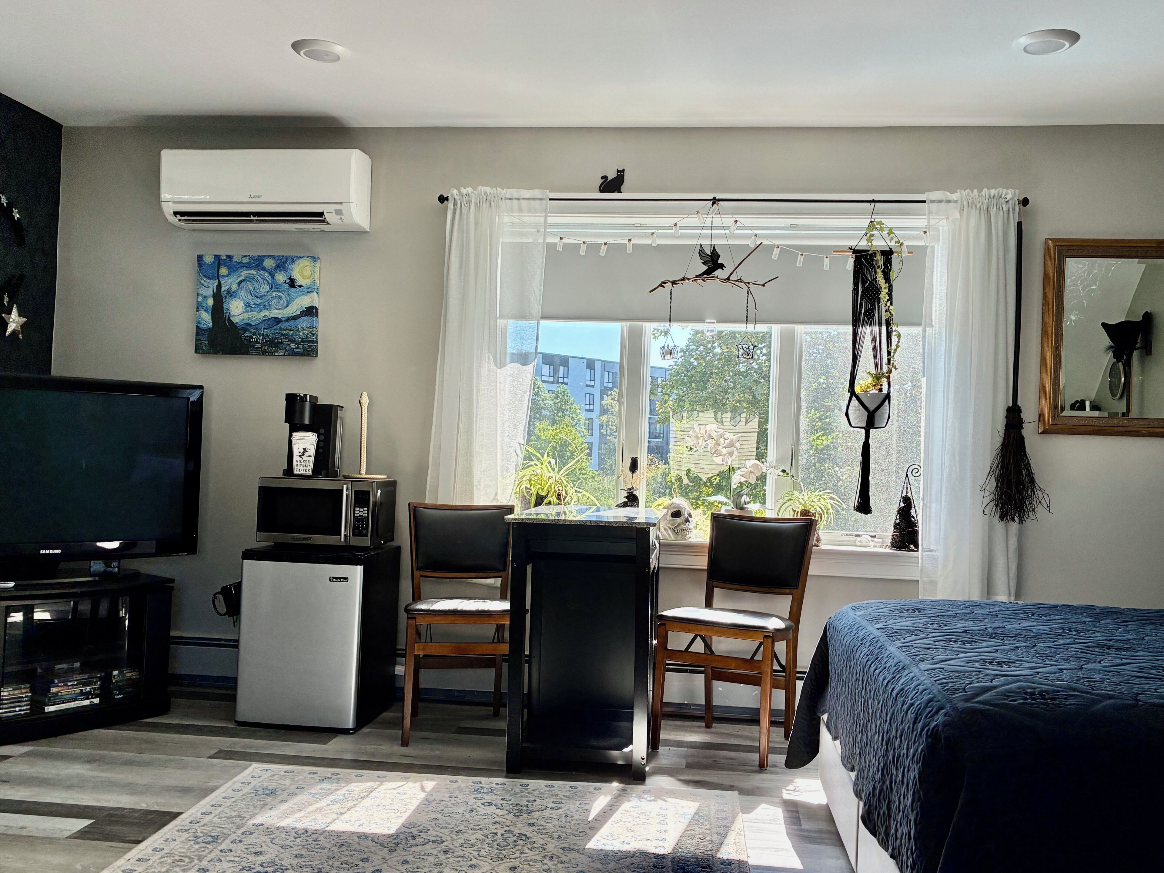 A room with a bed, a desk with a chair, a television, a refrigerator, and a window with curtains.