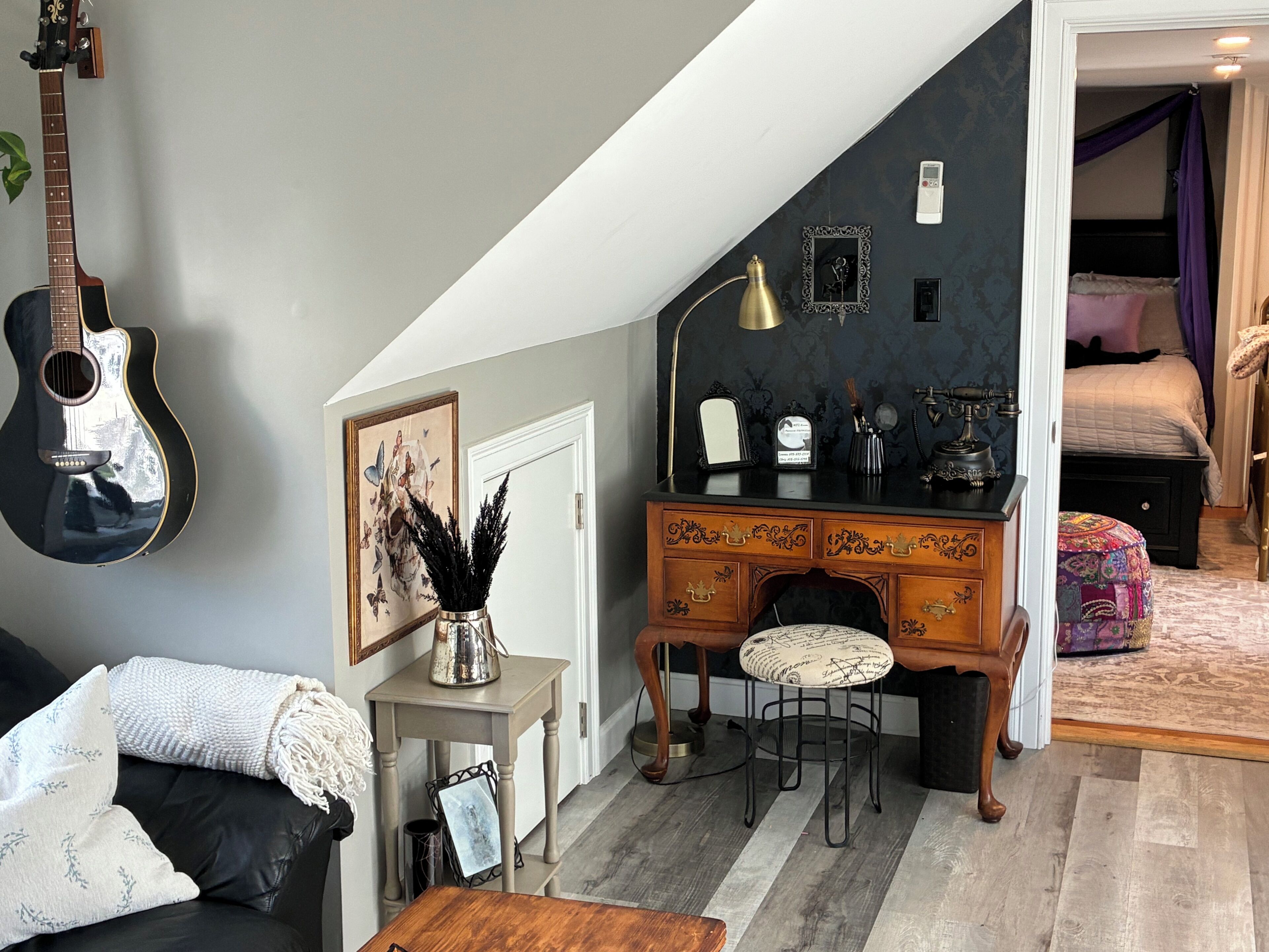 Ein gemütliches Zimmer mit Schreibtisch, Stuhl, Gitarre und Bett.