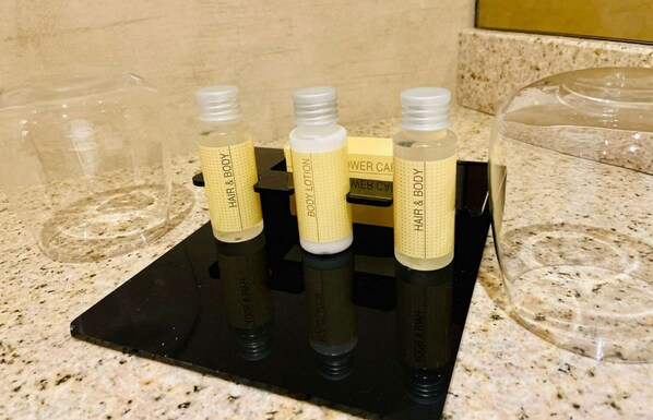 A set of toiletries on a black tray in a bathroom.