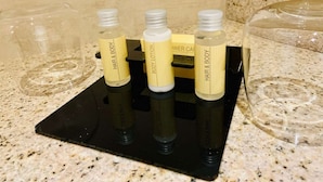 A black tray holding four bottles of body lotion and a bar of soap on a granite countertop. - Pension Katharinenschule (Eisenach)