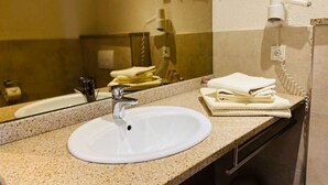 A bathroom with a white sink, a mirror, and a towel stack. - Pension Katharinenschule (Eisenach)